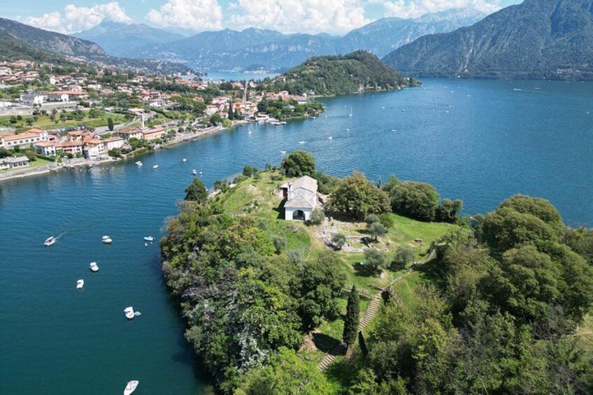 A lake surrounded by mountains, boats, and a small island with a building. 3