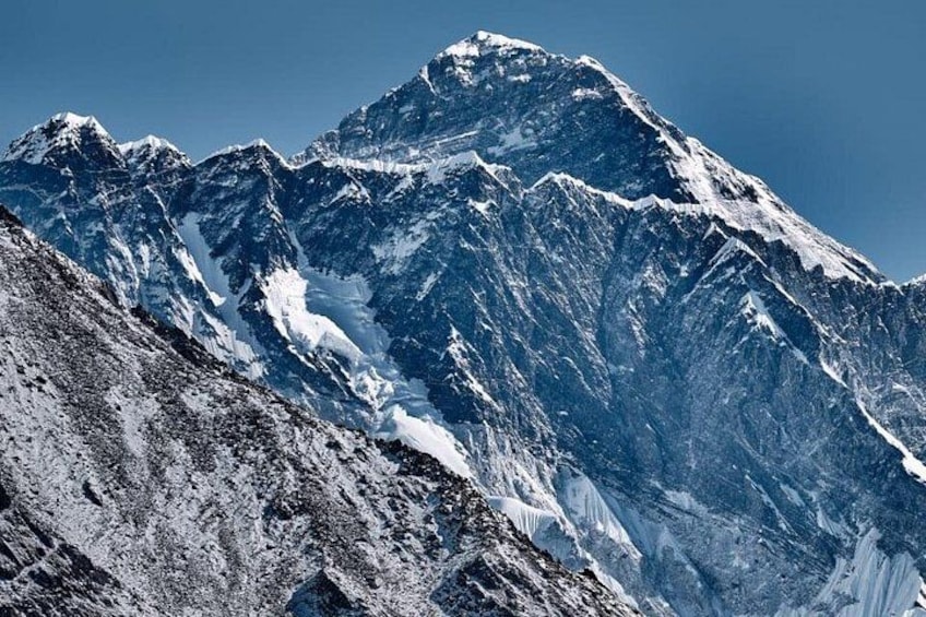 A snow-covered mountain peak with rugged terrain and a clear sky. 5