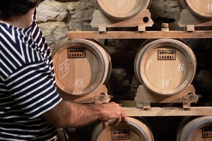 A person handling wooden barrels labeled with 'BOURGOGNE COGNAC' and numbers. 2
