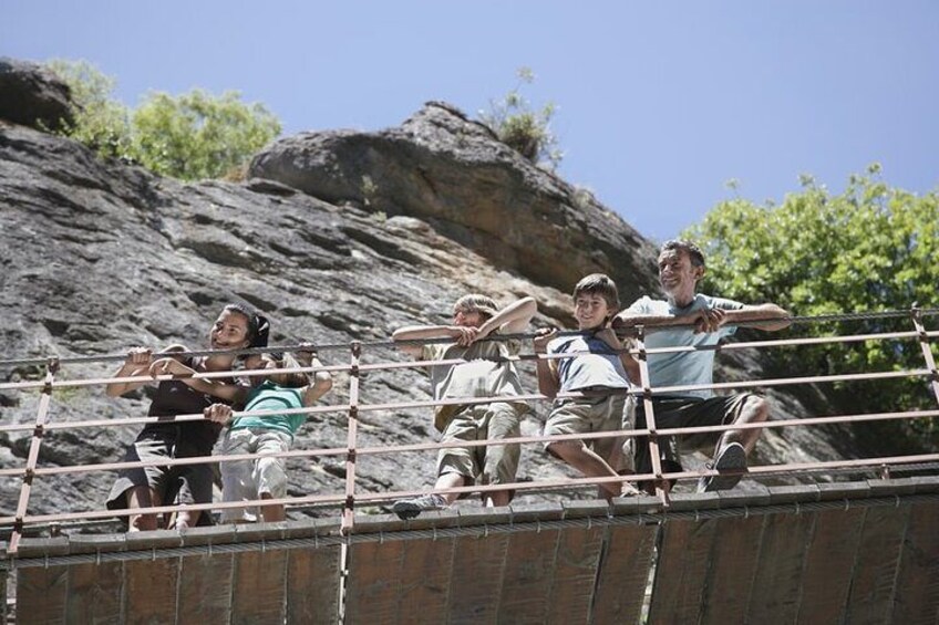 A group of people standing on a bridge with a rocky landscape in the background. 1