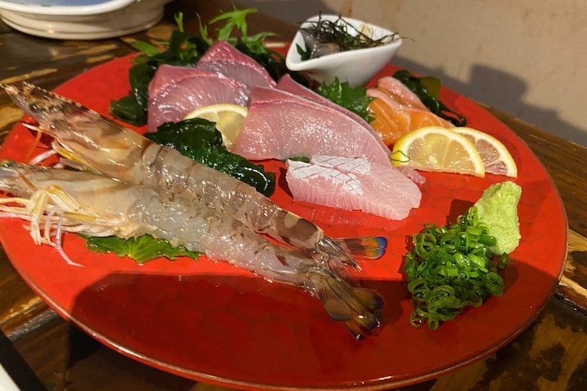 Une assiette de fruits de mer comprenant des crevettes, du poisson et des tranches de citron. 5