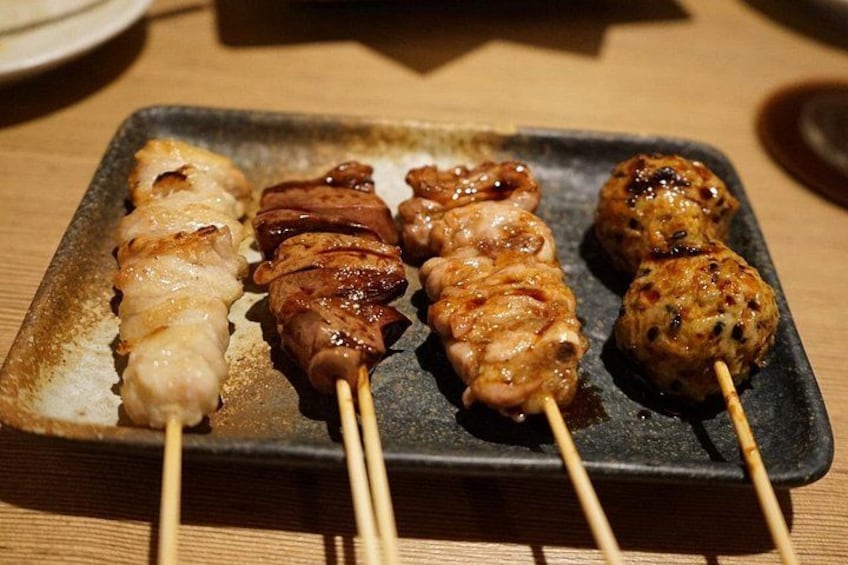 Une assiette noire sur laquelle sont présentées des brochettes de viande. 3