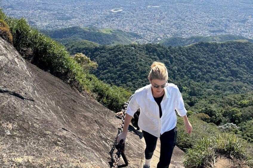A person hiking on a rocky slope with a cityscape in the background. 3