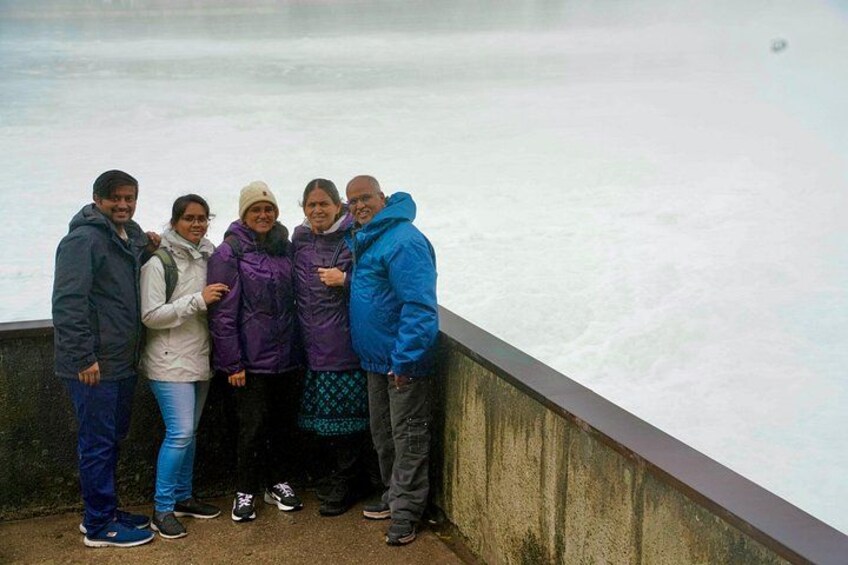 Een groep mensen staat op een betonnen rand langs een waterpartij. 5