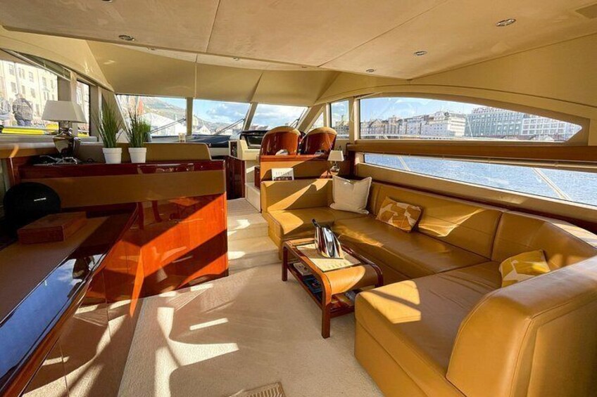 A yacht interior with a sofa, coffee table, and a view of the water outside. 2