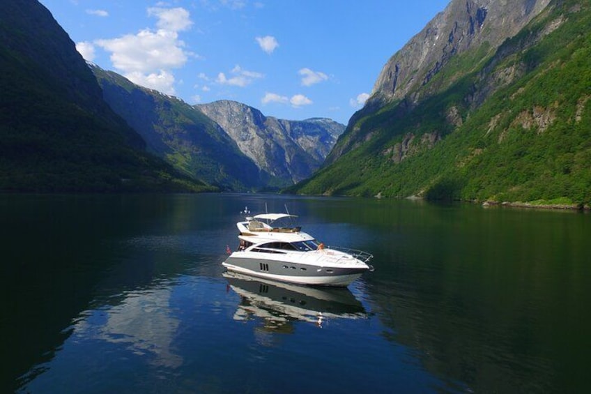 A calm lake with boats anchored in the middle, surrounded by steep green mountains under a clear sky. 2