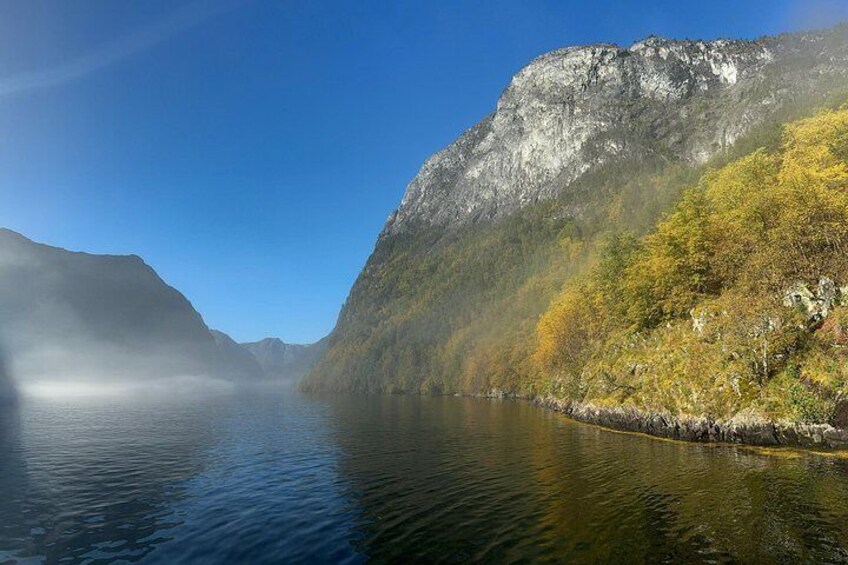 A calm lake surrounded by steep cliffs and autumn-colored trees. 5