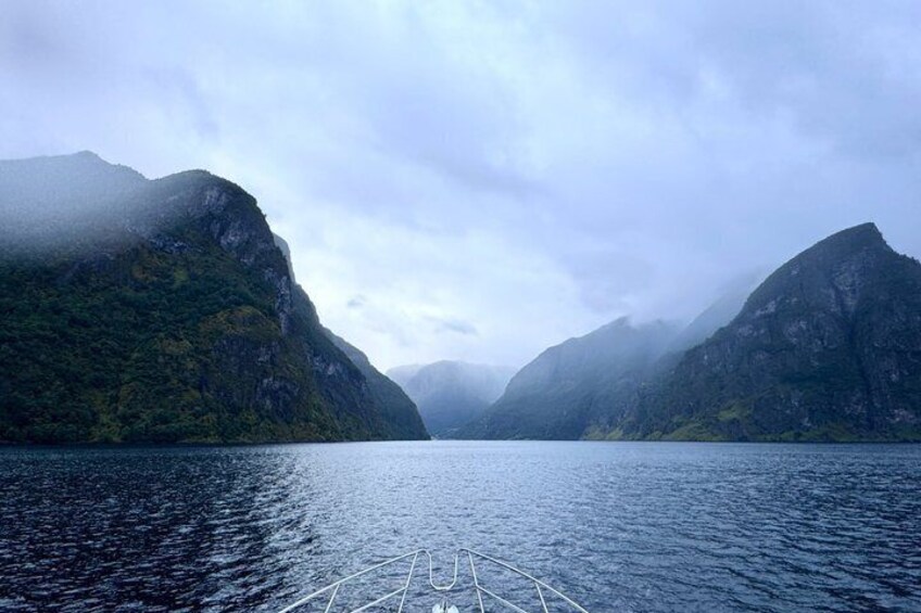 A calm lake surrounded by mountains with a boat in the foreground. 4