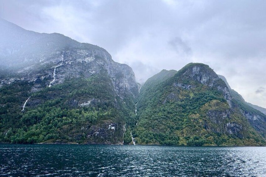 A mountainous landscape with a waterfall and a body of water. 3