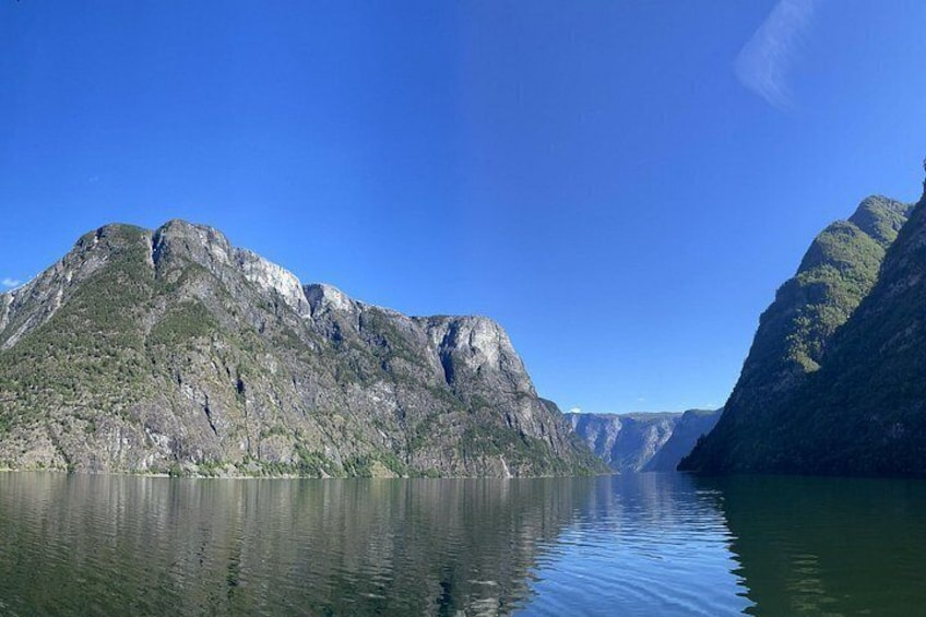 A calm lake surrounded by steep, rocky mountains under a clear blue sky. 4