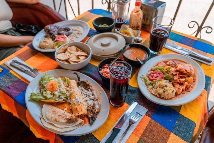 Una mesa colorida con varios platos, incluyendo tacos, una ensalada y un plato con salsa roja. 4
