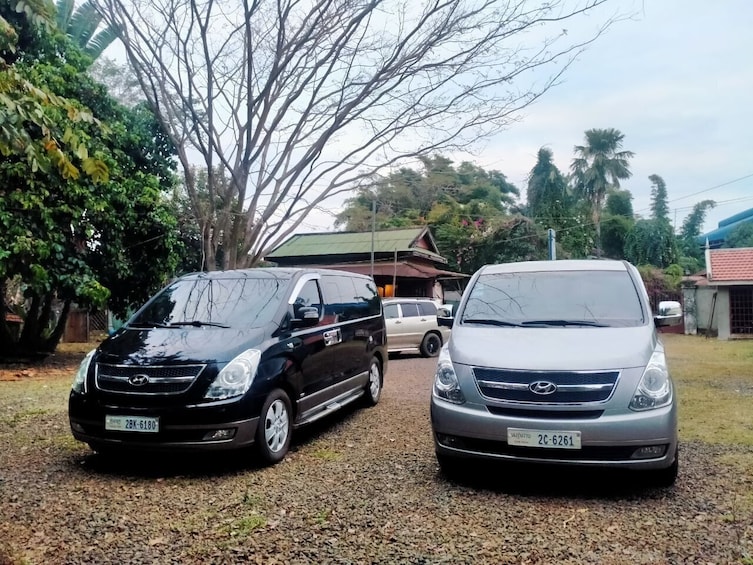 Kaksi autoa on pysäköitynä sorapäällysteiselle ajotielle, taustalla näkyy talo ja puita. 3