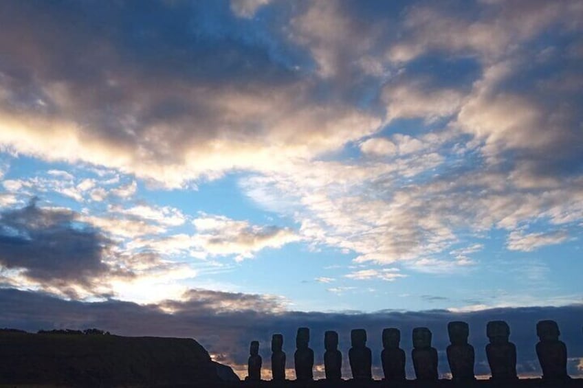 A row of Easter Island statues under a cloudy sky. 2