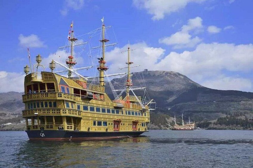 A large, multi-decked ship with multiple masts and flags, sailing on a body of water with mountains in the background. 3