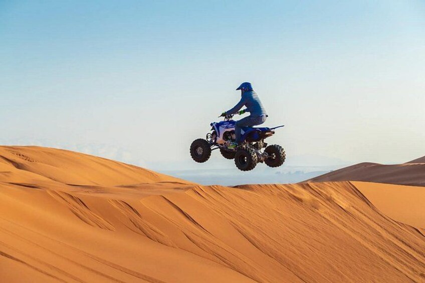 A person riding a quad bike over sand dunes. 4