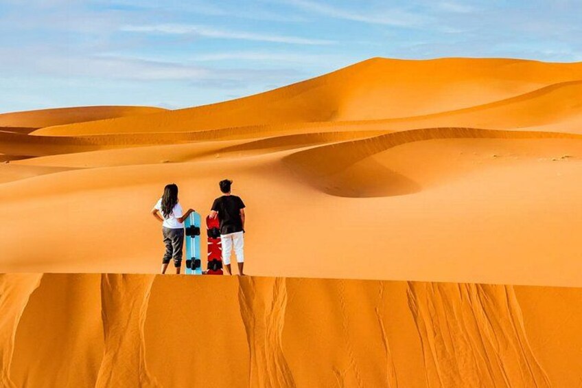 Two people standing on a sand dune with a red and blue object in the foreground. 3