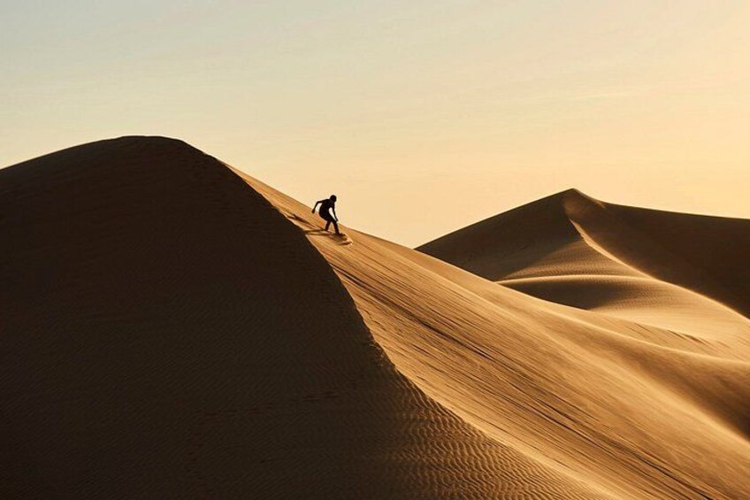 A person climbing a sand dune in a desert landscape. 5