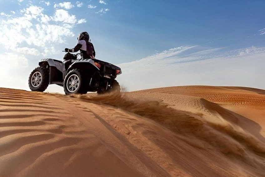 Iemand rijdt op een quad over een zandduin. 5