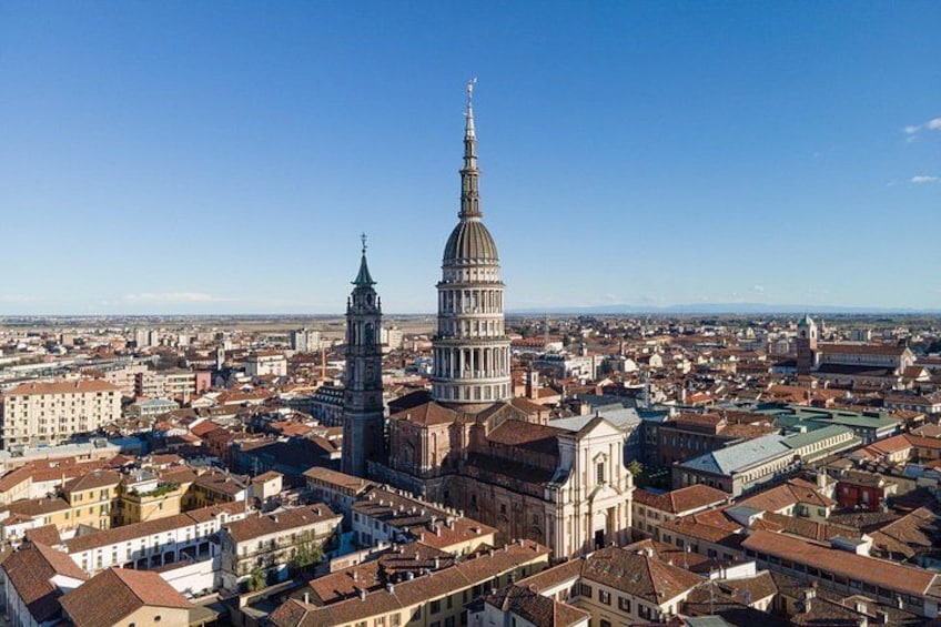 A cityscape with a prominent church featuring a tall spire, surrounded by historic buildings and a clear blue sky. 2