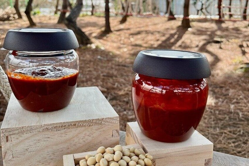Deux bocaux en verre, munis de couvercles, sont posés sur une surface en bois à l’extérieur. 4