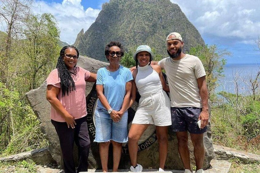 Four people standing in front of a large rock with the words 'WORLD HERITAGE' on it. 1