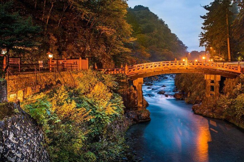A stone bridge over a river, surrounded by lush greenery and trees. 1