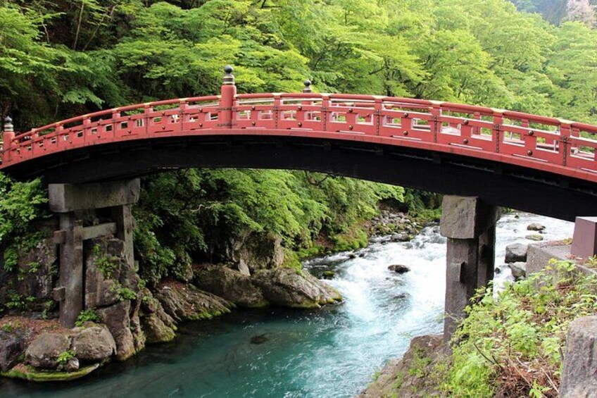 A red bridge over a river surrounded by lush greenery. 4