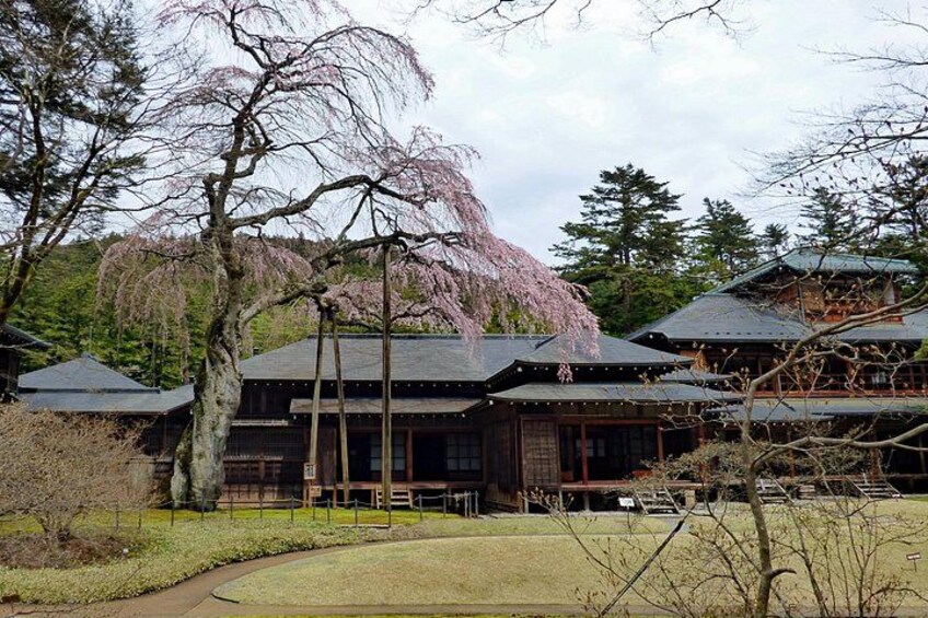 A traditional Japanese building with a thatched roof, surrounded by a well-maintained garden with a pathway. 4