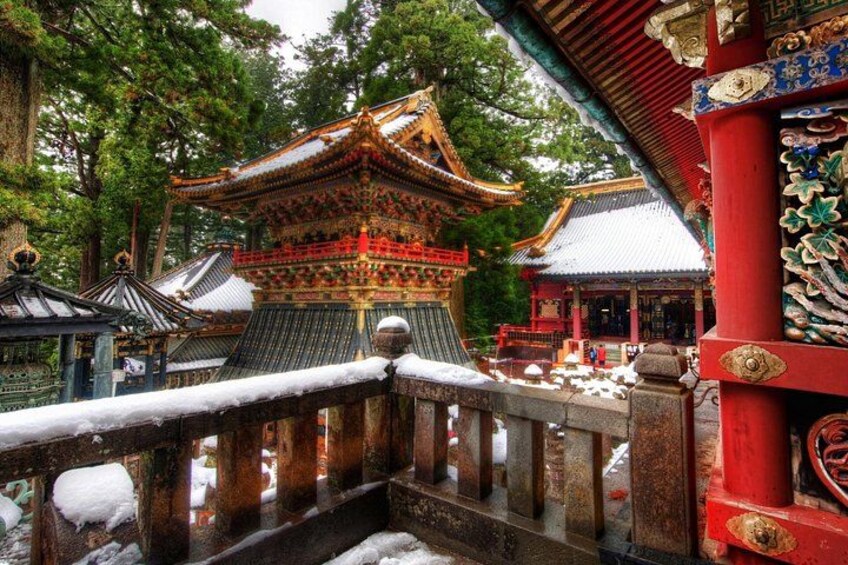 A traditional Japanese temple with ornate architecture, a snow-covered bridge, and a red gate. 3
