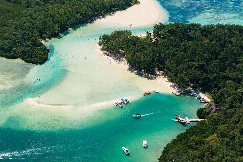 A coastal area with clear turquoise waters, a sandy beach, and several boats anchored near the shore. 2