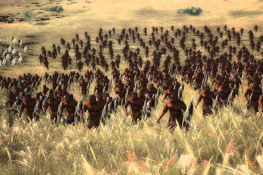 A large group of people in a field with some scattered trees and a few small bushes. 2