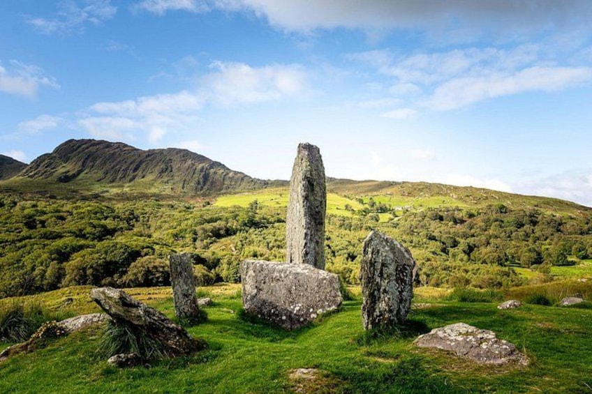 A standing stone monument in a grassy field with hills in the background. 4