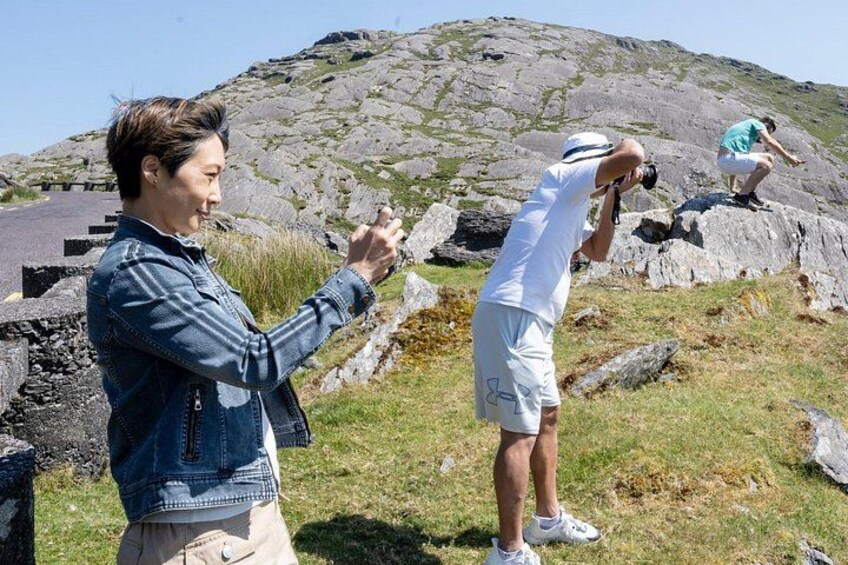 Two people taking photographs in a rocky outdoor setting. 2