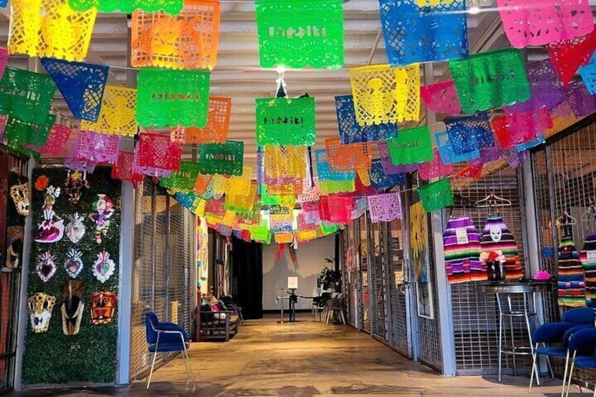 Un marché où des décorations en papier aux couleurs vives sont suspendues au plafond et où divers articles sont exposés sur des étagères. 1