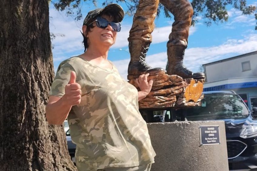 A person giving a thumbs-up next to a tree and a statue. 3