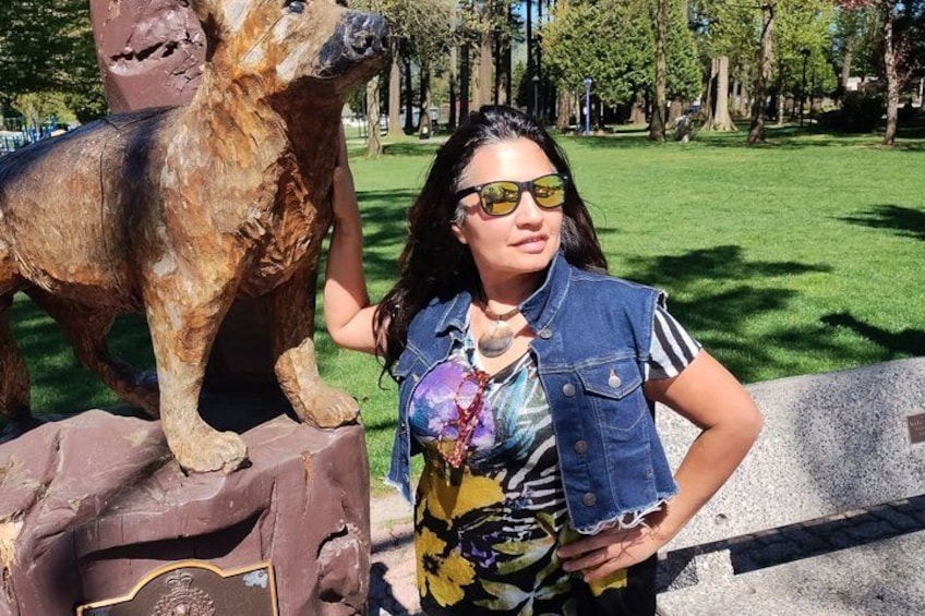 A person standing next to a bronze statue of a dog in a park. 4