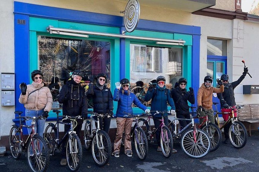 A group of cyclists in front of a building with a blue and yellow facade. 5