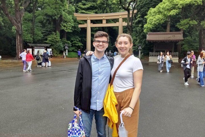 Un couple se tient devant un portail torii, avec un sanctuaire en arrière-plan. 1