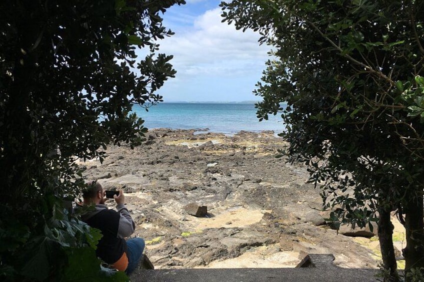 Una playa rocosa con una persona tomando una fotografía. 5