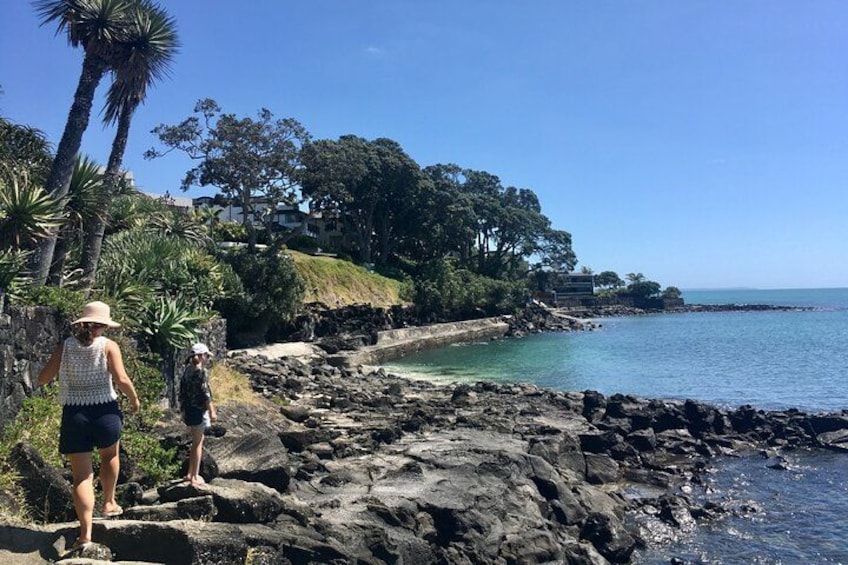 Una costa rocosa con palmeras y un cielo azul despejado. 3