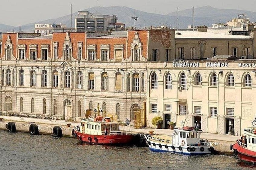 A waterfront with a large building, boats docked, and a mountainous background. 2