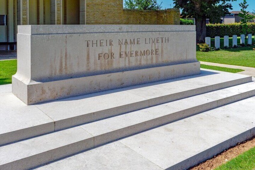 A stone monument with the inscription "Their Name Liveth For Evermore" on a grassy area with steps leading up to it. 5