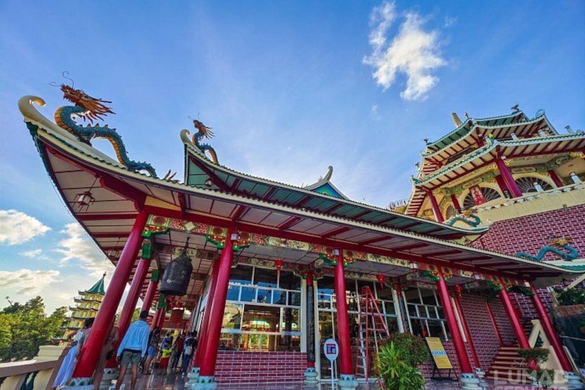 Een traditioneel Chinees gebouw met een versierde architectuur, waaronder een drakenmotief op het dak en rode zuilen. 4