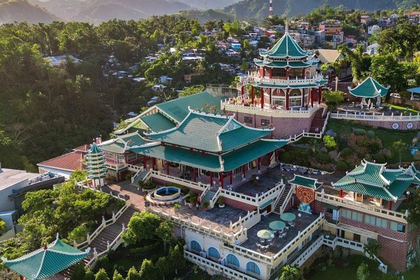 Een traditionele Chinese pagode met meerdere verdiepingen, omgeven door weelderige begroeiing en woongebouwen. 3