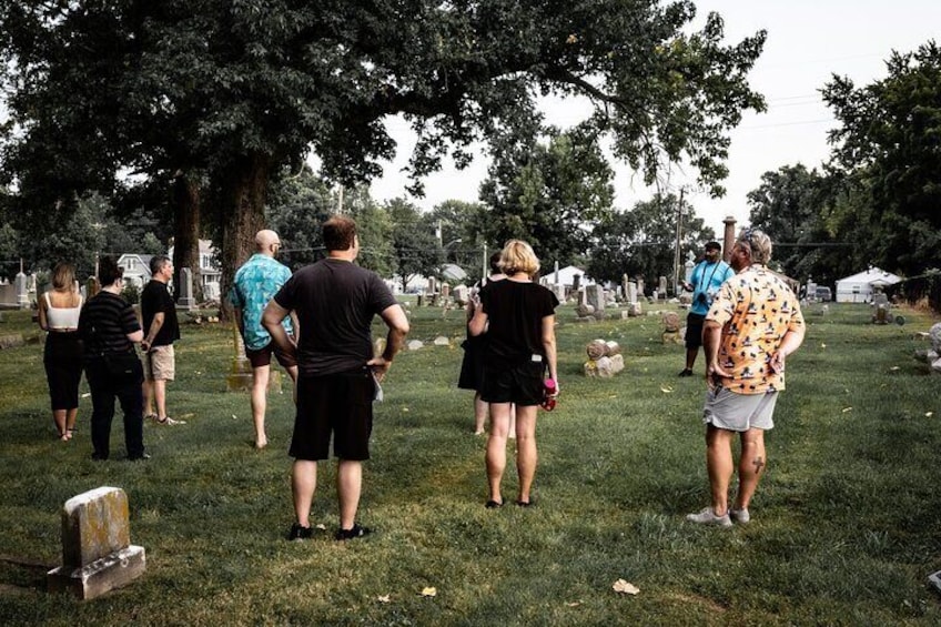 People walking in a cemetery with tombstones and trees. 3