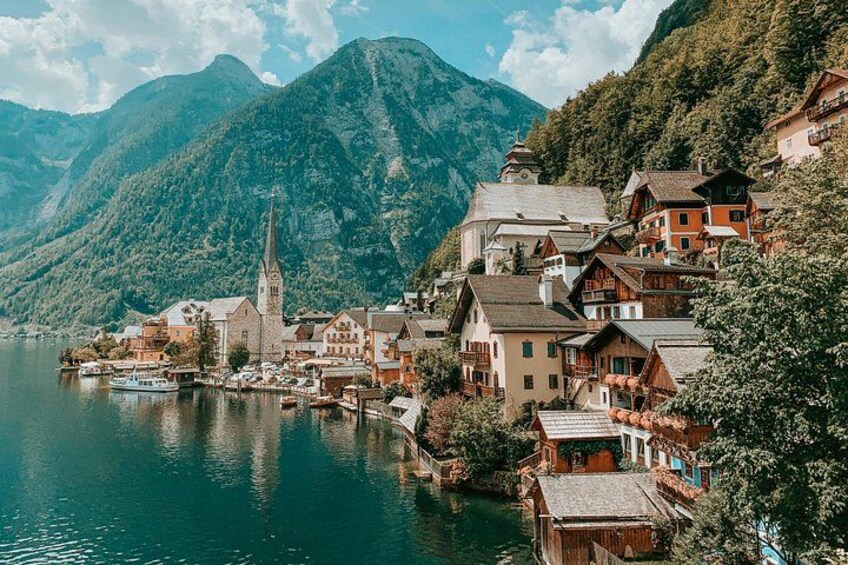A lakeside village with traditional houses, a church, and boats docked along the shore. 2