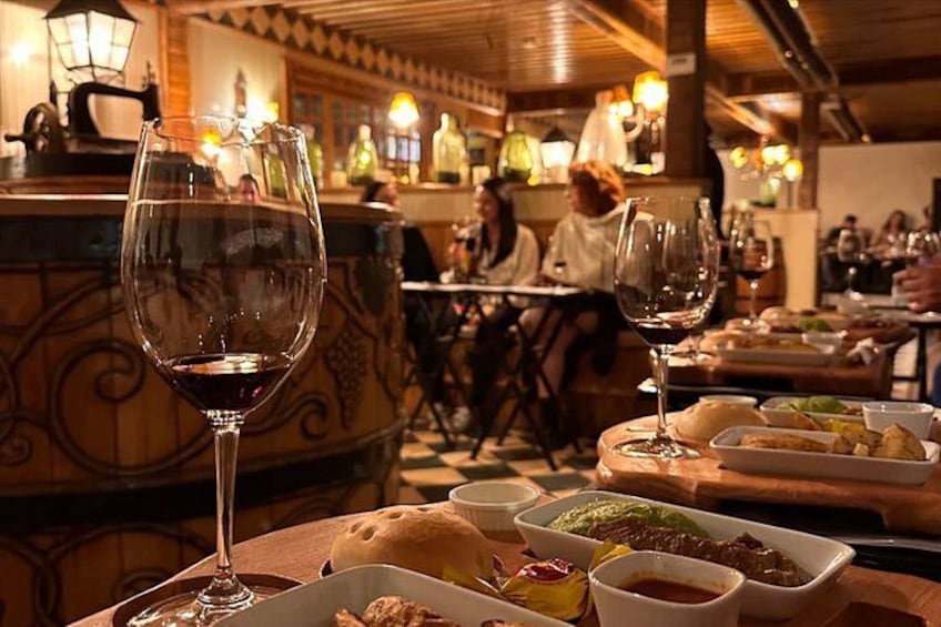 A restaurant interior with tables, wine glasses, and food dishes. 3