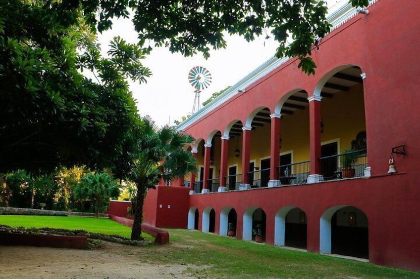 A red building with a windmill, arched columns, and a well-maintained lawn. 2