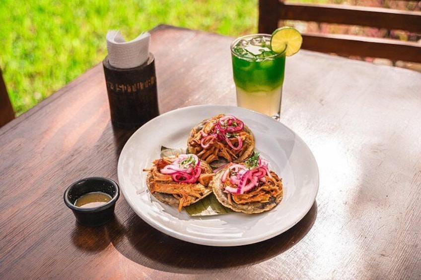 A plate of tacos with a drink and a bottle on a wooden table. 4