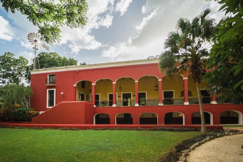 A red building with a yellow facade, arched windows, and a windmill. 1
